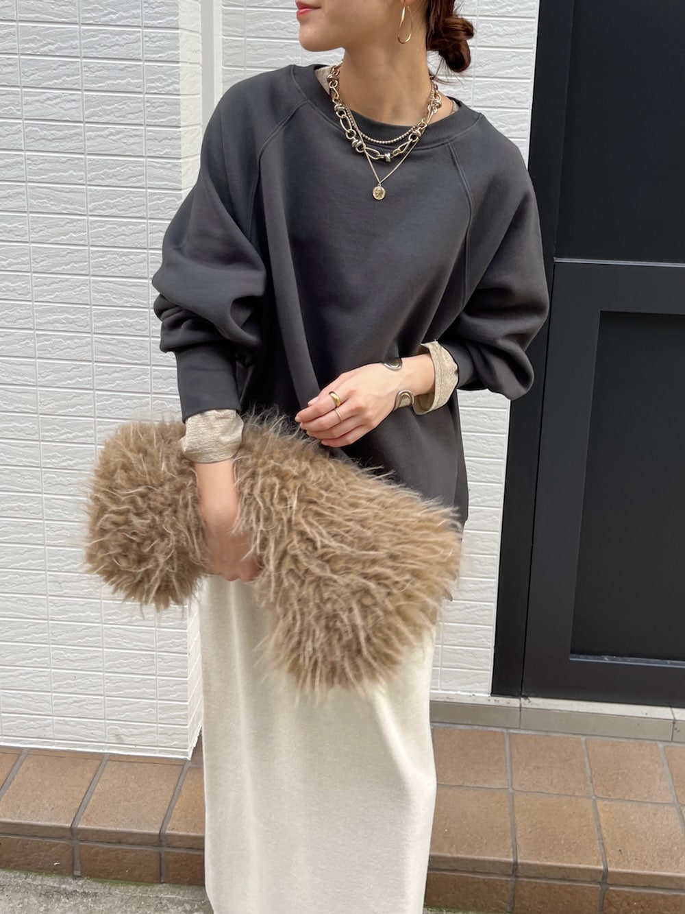 グレー系のTシャツ/カットソー、ホワイト系のスカート、ブラック系のブーツを着用したレディースの冬コーディネートの5枚目の写真