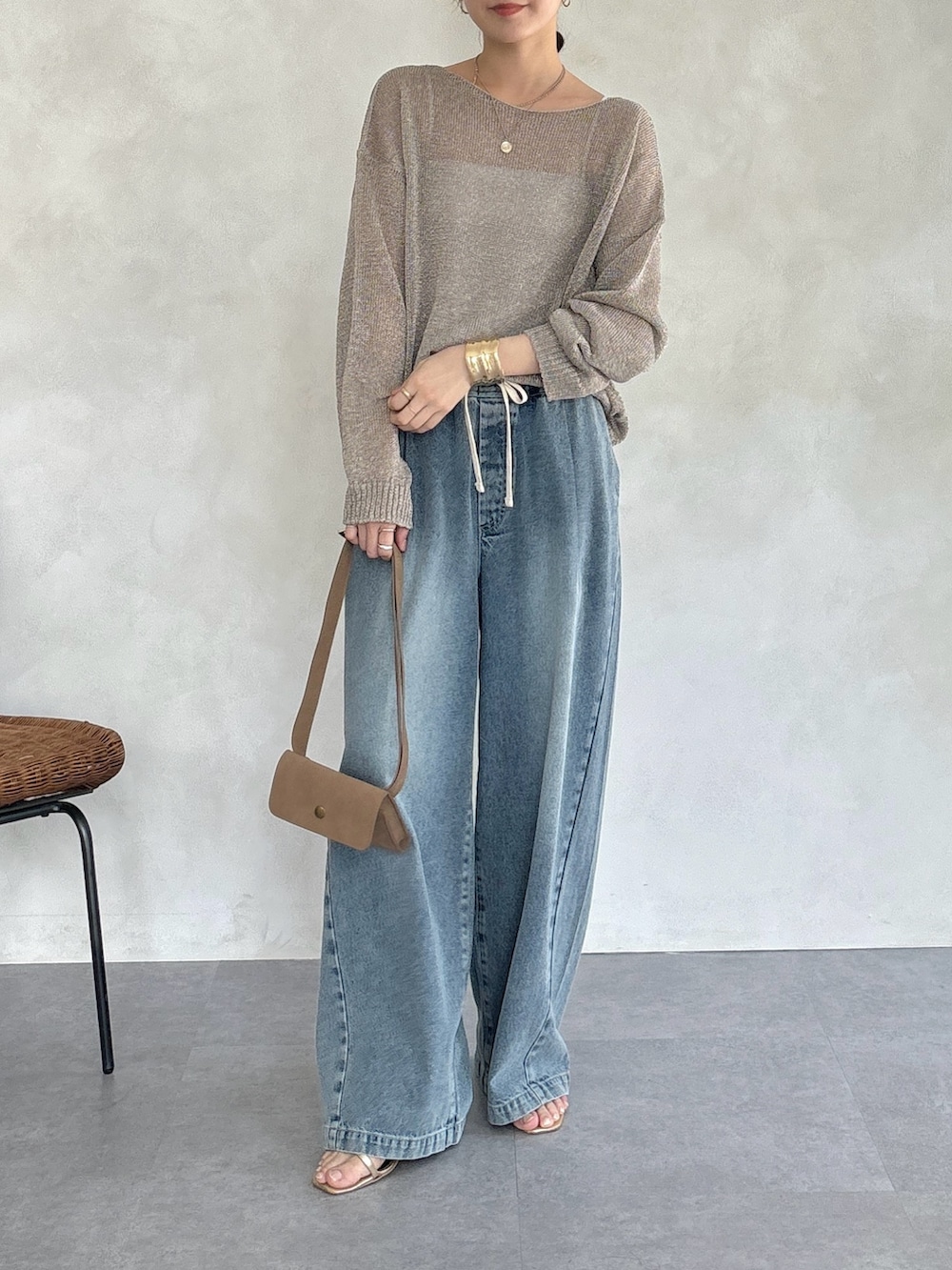 ゴールド系のニット/セーター、ブルー系のデニムパンツ、ゴールド系のネックレスを着用したレディースの春コーディネートの2枚目の写真