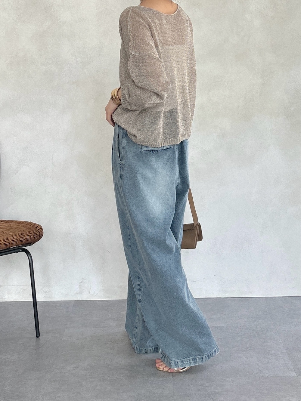 ゴールド系のニット/セーター、ブルー系のデニムパンツ、ゴールド系のネックレスを着用したレディースの春コーディネートの4枚目の写真