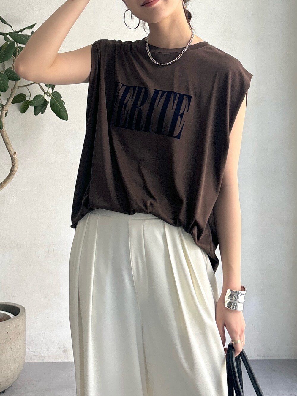 ホワイト系のスラックス、ブラウン系のTシャツ/カットソー、ブラック系のショルダーバッグを着用したレディースの夏コーディネートの6枚目の写真