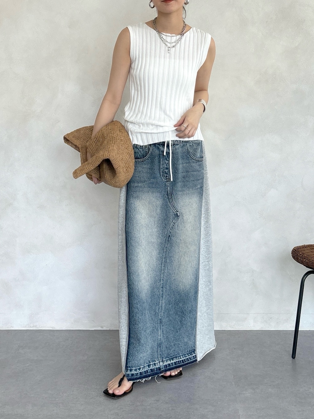 グレー系のスカート、ホワイト系のニット/セーター、シルバー系のネックレスを着用したレディースの春コーディネートの3枚目の写真