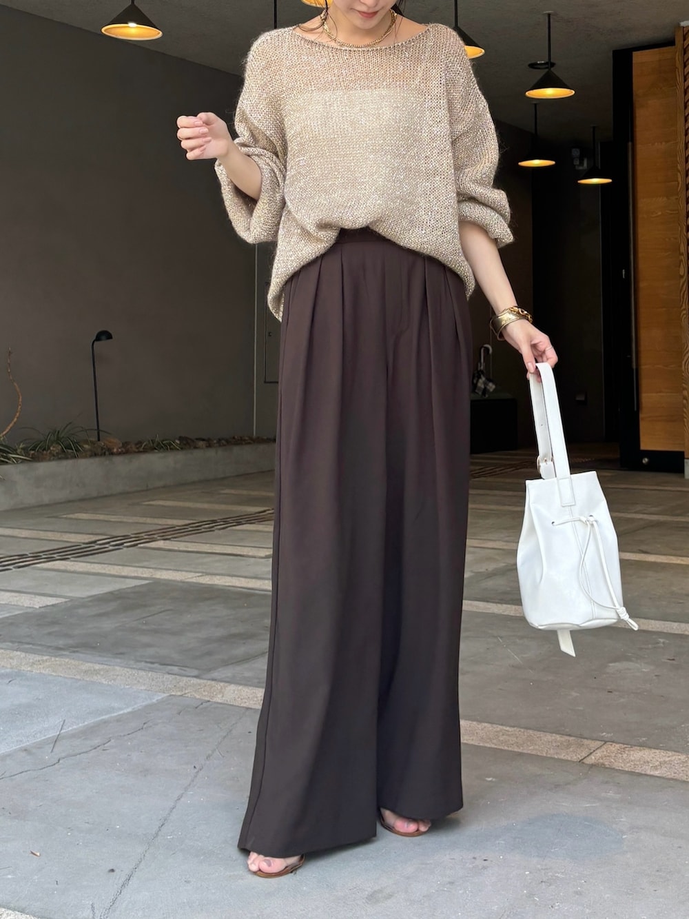 ブラウン系のスラックス、ベージュ系のニット/セーター、ホワイト系のショルダーバッグを着用したレディースの夏コーディネートの5枚目の写真