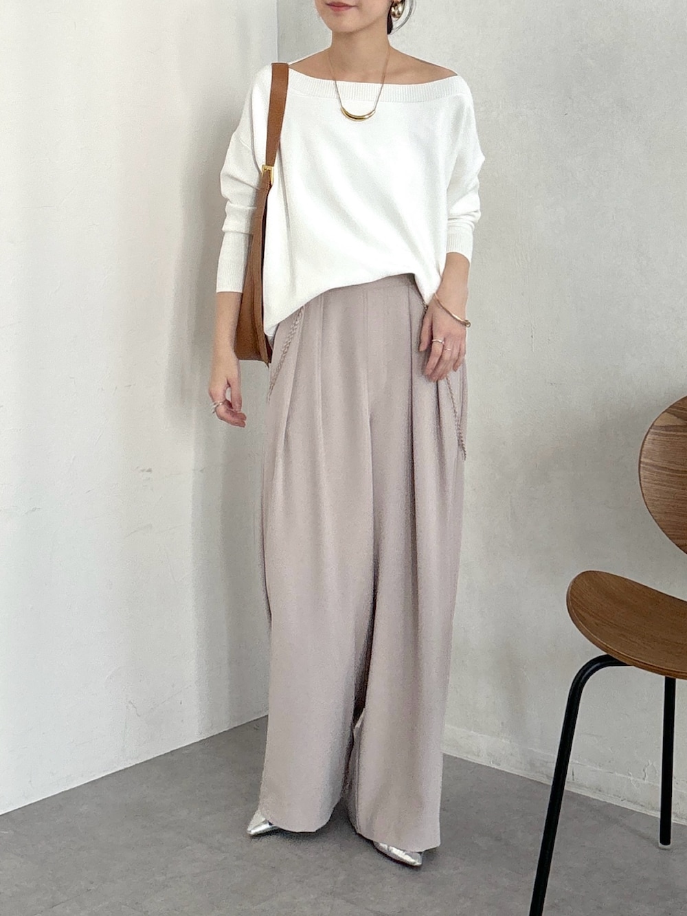 イエロー系のショルダーバッグ、ベージュ系のスラックス、ゴールド系のブレスレットを着用したレディースの冬コーディネートの3枚目の写真