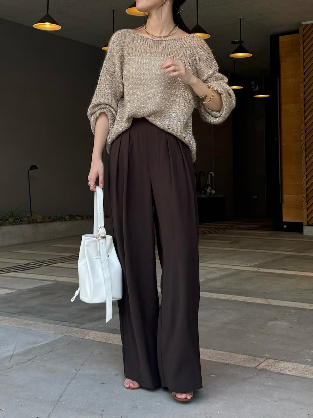 ブラウン系のスラックス、ベージュ系のニット/セーター、ホワイト系のショルダーバッグを着用したレディースの夏コーディネートの6枚目の写真
