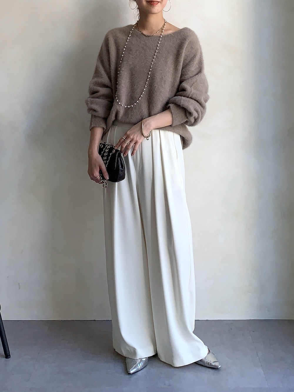 ブラウン系のニット/セーター、ブラウン系のショルダーバッグ、ホワイト系のスラックスを着用したレディースの秋コーディネートの4枚目の写真