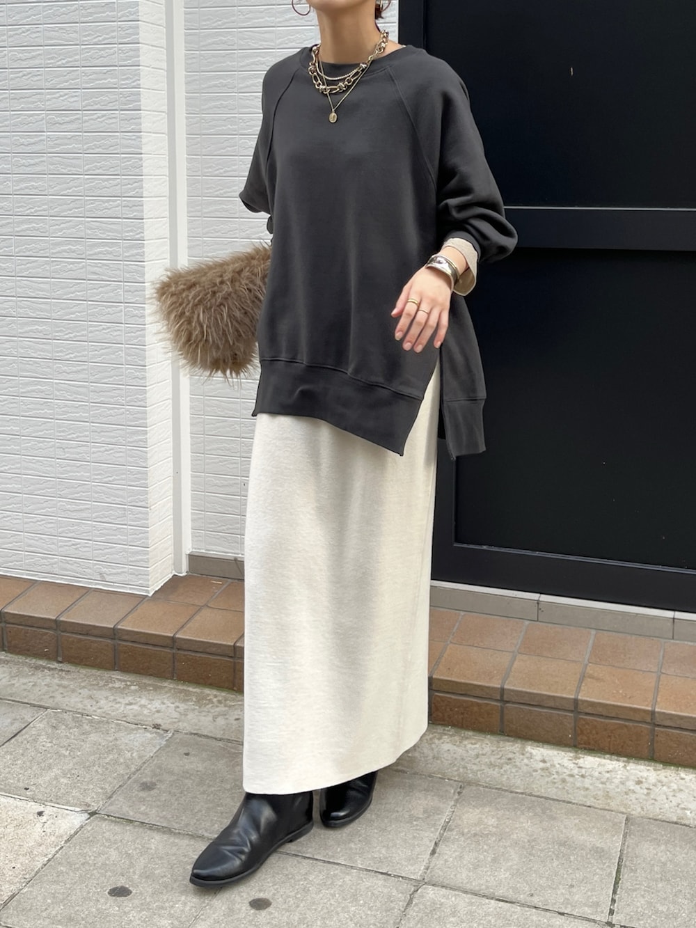 グレー系のTシャツ/カットソー、ホワイト系のスカート、ブラック系のブーツを着用したレディースの冬コーディネートの2枚目の写真