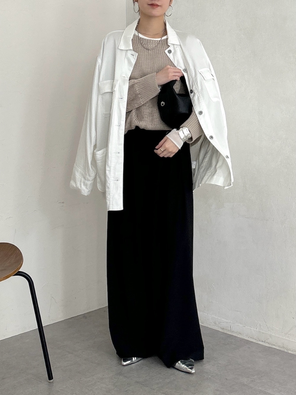 ブラック系のスラックス、ベージュ系のニット/セーター、ホワイト系のTシャツ/カットソーを着用したレディースの春コーディネートの2枚目の写真