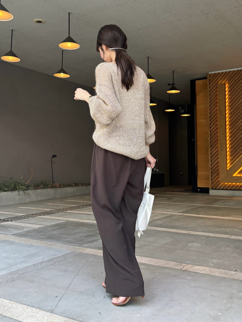 ブラウン系のスラックス、ベージュ系のニット/セーター、ホワイト系のショルダーバッグを着用したレディースの夏コーディネートの7枚目の写真