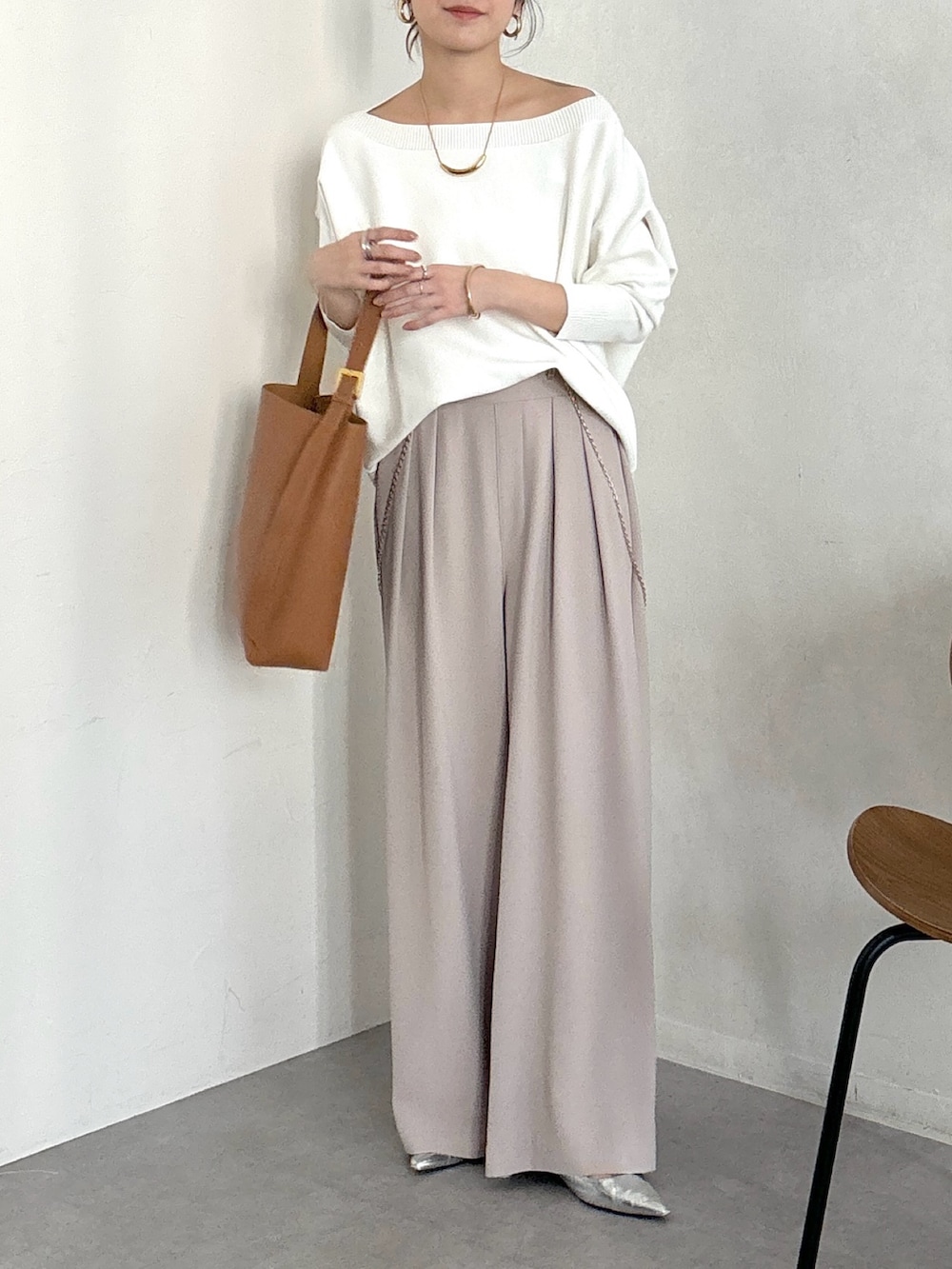 イエロー系のショルダーバッグ、ベージュ系のスラックス、ゴールド系のブレスレットを着用したレディースの冬コーディネートの2枚目の写真