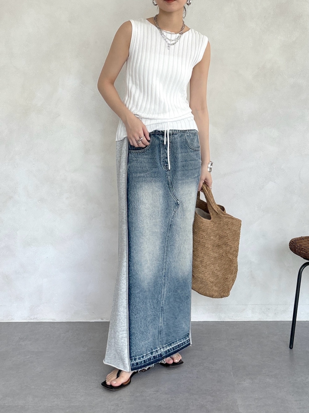 グレー系のスカート、ホワイト系のニット/セーター、シルバー系のネックレスを着用したレディースの春コーディネートの2枚目の写真