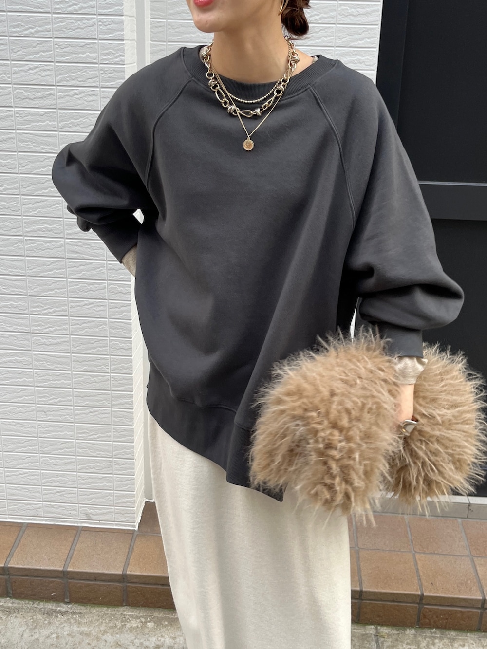 グレー系のTシャツ/カットソー、ホワイト系のスカート、ブラック系のブーツを着用したレディースの冬コーディネートの6枚目の写真