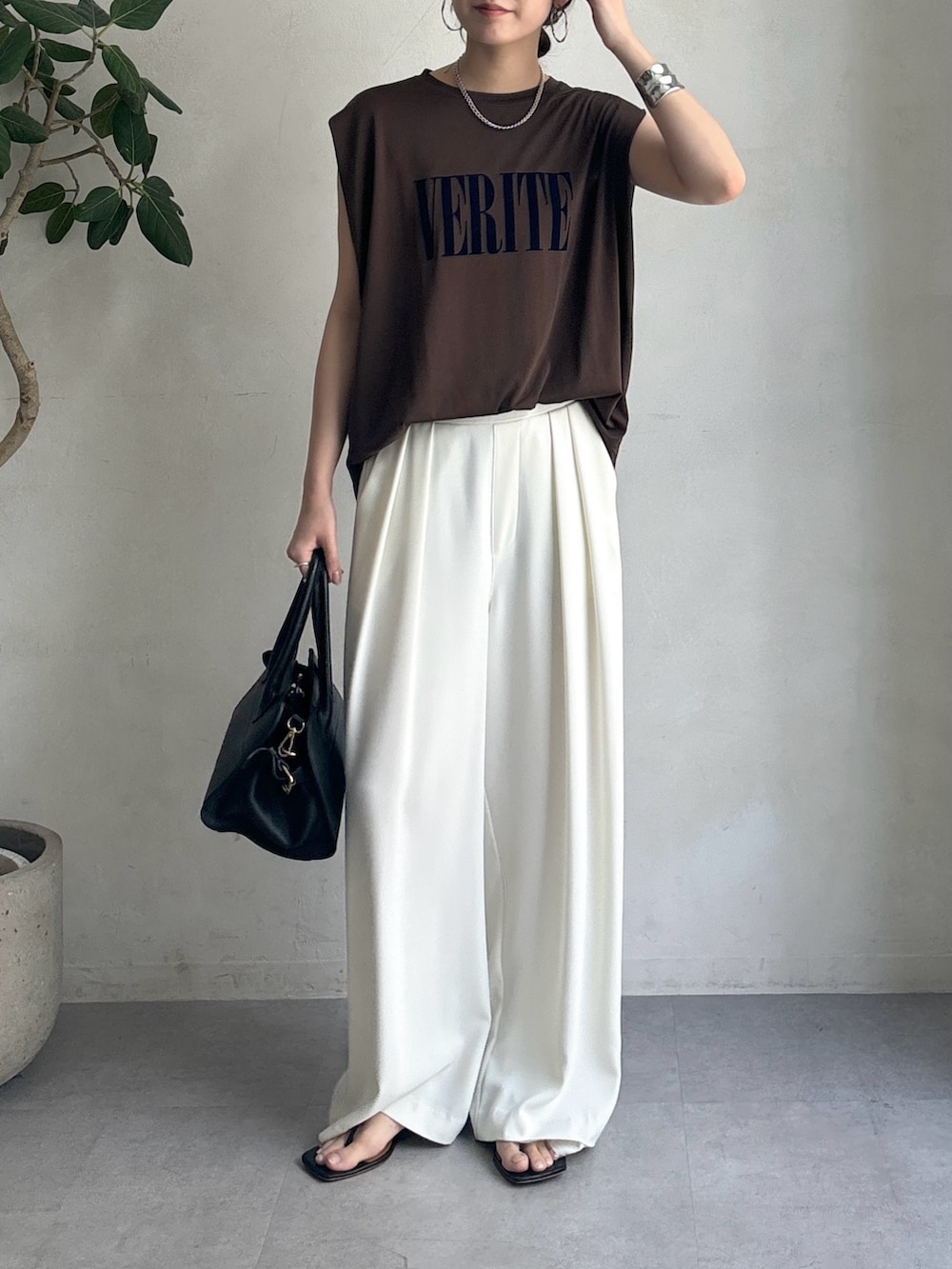ホワイト系のスラックス、ブラウン系のTシャツ/カットソー、ブラック系のショルダーバッグを着用したレディースの夏コーディネートの3枚目の写真