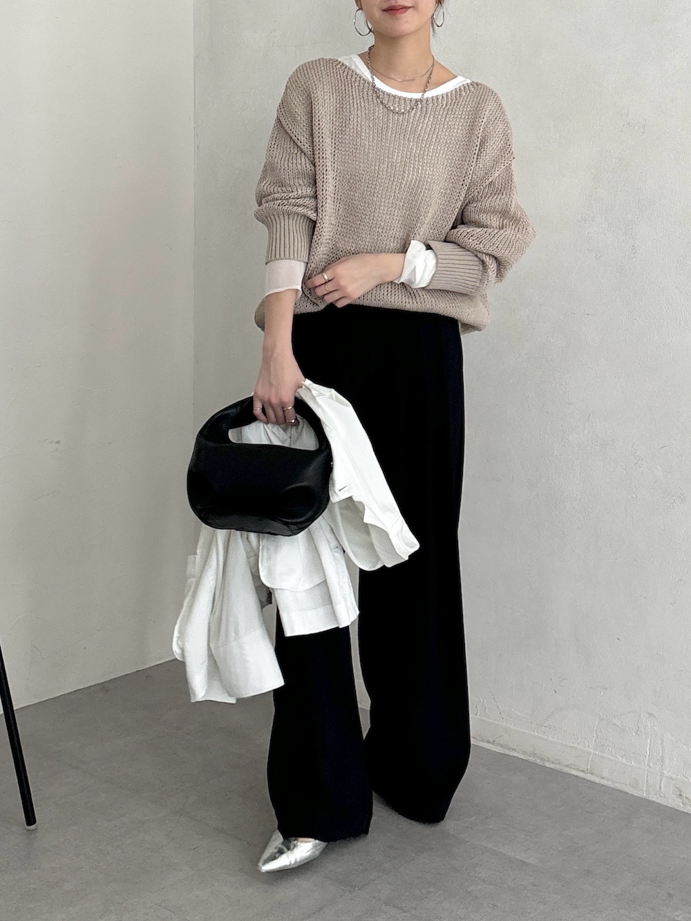ブラック系のスラックス、ベージュ系のニット/セーター、ホワイト系のTシャツ/カットソーを着用したレディースの春コーディネートの5枚目の写真