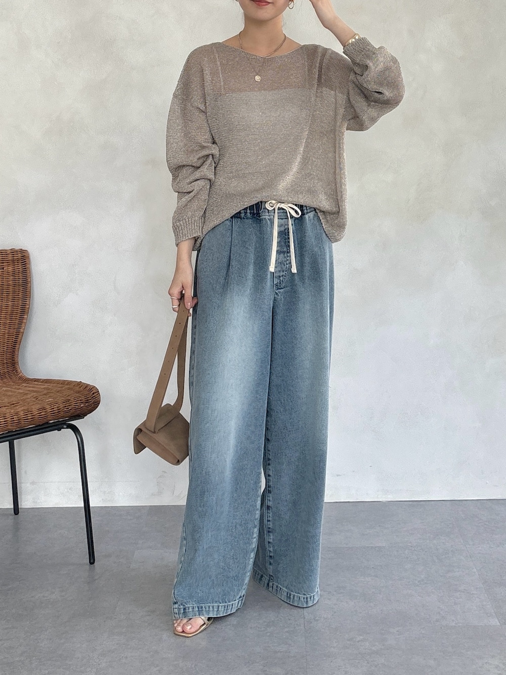 ゴールド系のニット/セーター、ブルー系のデニムパンツ、ゴールド系のネックレスを着用したレディースの春コーディネートの3枚目の写真