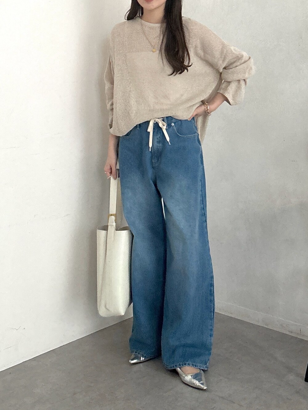 ベージュ系のニット/セーター、ホワイト系のショルダーバッグ、ブルー系のデニムパンツを着用したレディースの春コーディネートの5枚目の写真