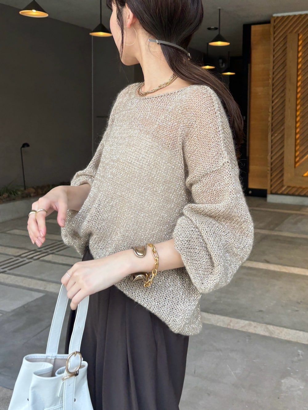 ブラウン系のスラックス、ベージュ系のニット/セーター、ホワイト系のショルダーバッグを着用したレディースの夏コーディネートの8枚目の写真