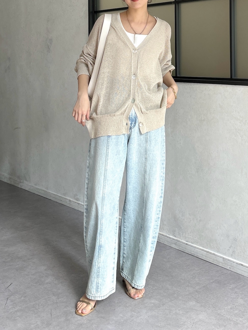 ブルー系のデニムパンツ、ホワイト系のショルダーバッグ、ベージュ系のカーディガン/ボレロを着用したレディースの春コーディネートの2枚目の写真