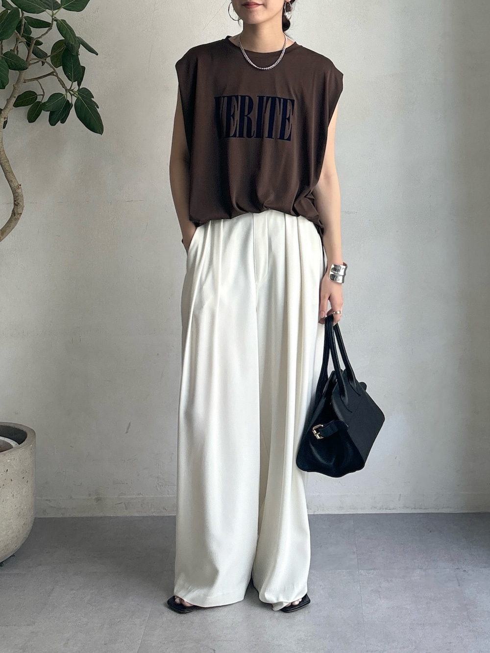 ホワイト系のスラックス、ブラウン系のTシャツ/カットソー、ブラック系のショルダーバッグを着用したレディースの夏コーディネートの2枚目の写真