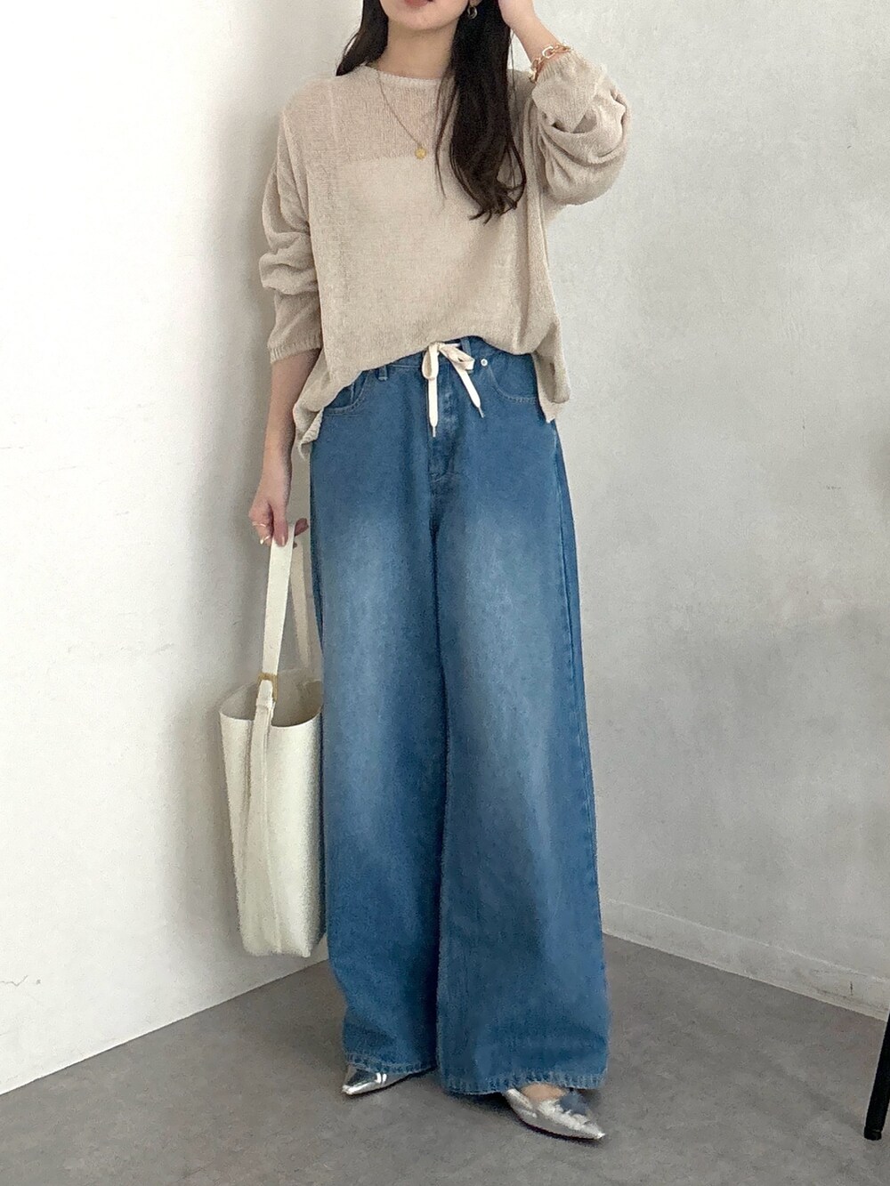 ベージュ系のニット/セーター、ホワイト系のショルダーバッグ、ブルー系のデニムパンツを着用したレディースの春コーディネートの2枚目の写真