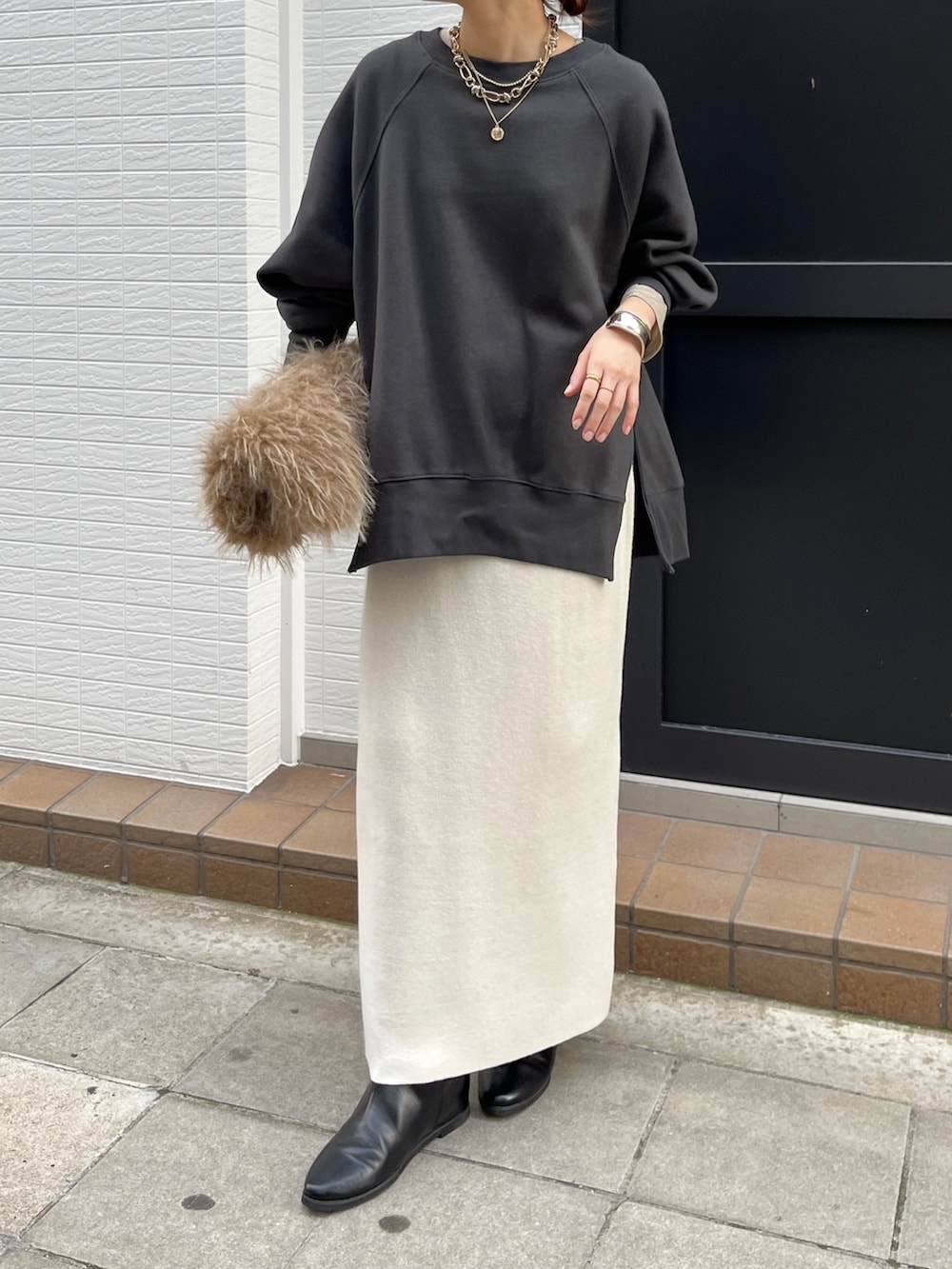 グレー系のTシャツ/カットソー、ホワイト系のスカート、ブラック系のブーツを着用したレディースの冬コーディネートの3枚目の写真