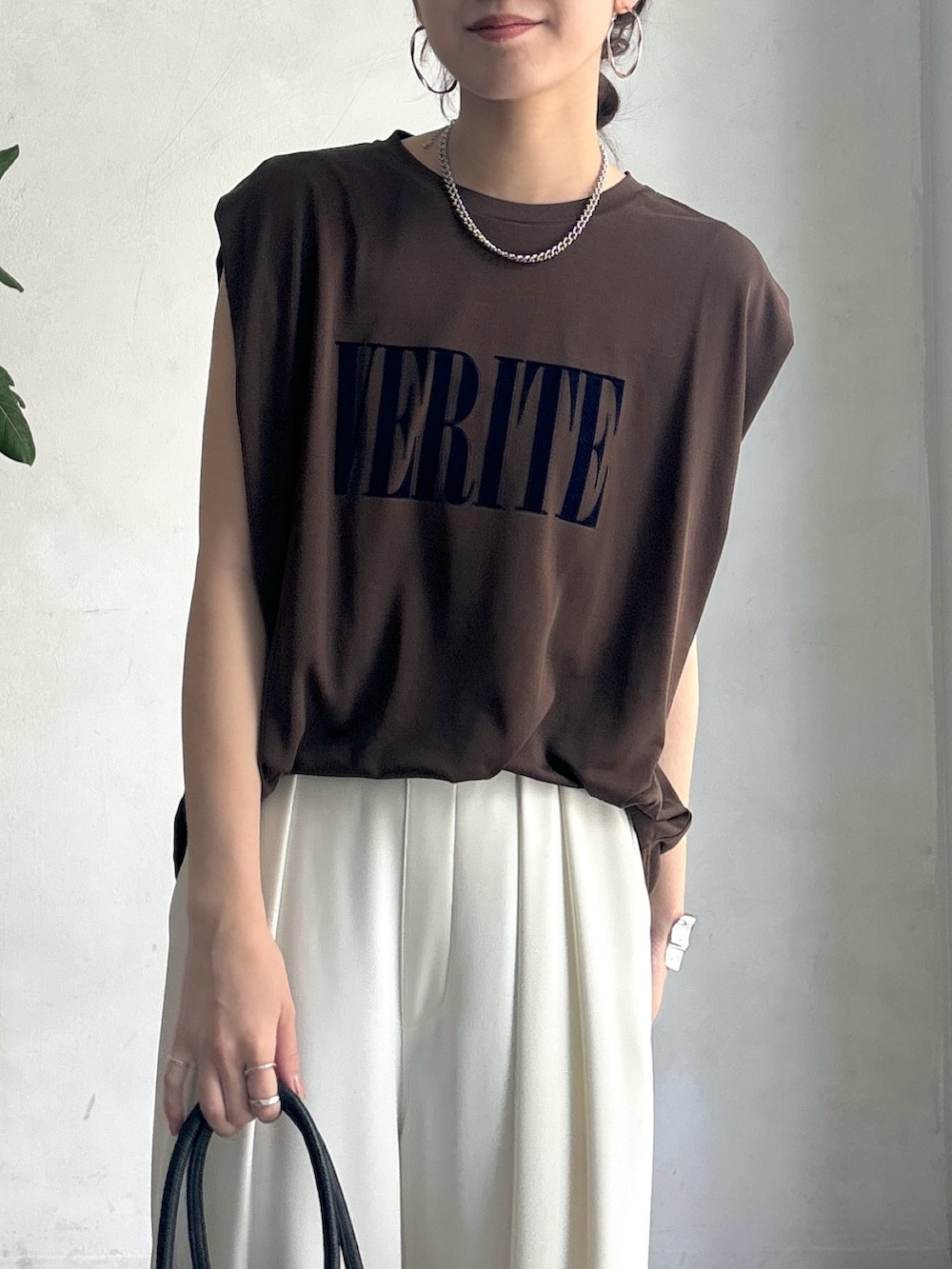 ホワイト系のスラックス、ブラウン系のTシャツ/カットソー、ブラック系のショルダーバッグを着用したレディースの夏コーディネートの5枚目の写真