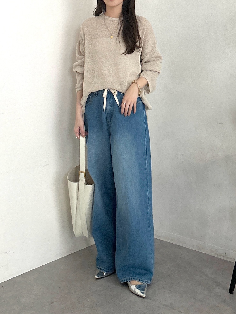 ベージュ系のニット/セーター、ホワイト系のショルダーバッグ、ブルー系のデニムパンツを着用したレディースの春コーディネートの3枚目の写真