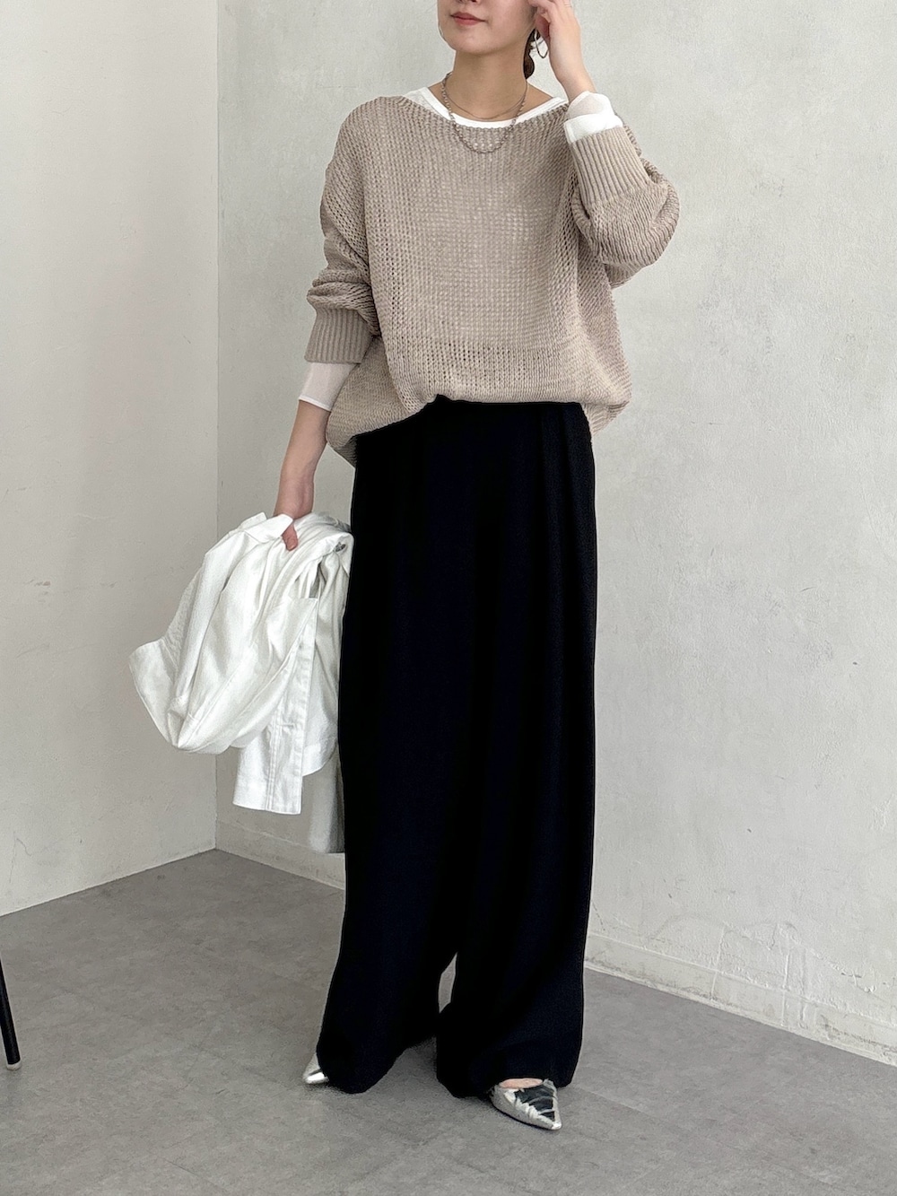 ブラック系のスラックス、ベージュ系のニット/セーター、ホワイト系のTシャツ/カットソーを着用したレディースの春コーディネートの6枚目の写真