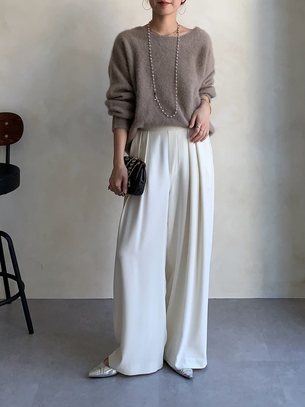 ブラウン系のニット/セーター、ブラウン系のショルダーバッグ、ホワイト系のスラックスを着用したレディースの秋コーディネートの3枚目の写真