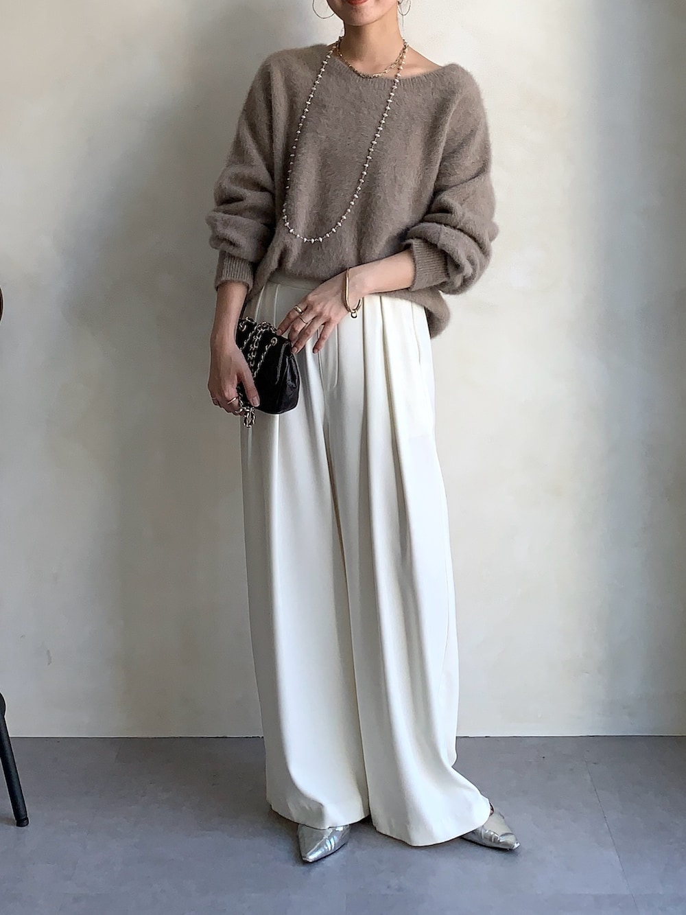 ブラウン系のニット/セーター、ブラウン系のショルダーバッグ、ホワイト系のスラックスを着用したレディースの秋コーディネートの2枚目の写真