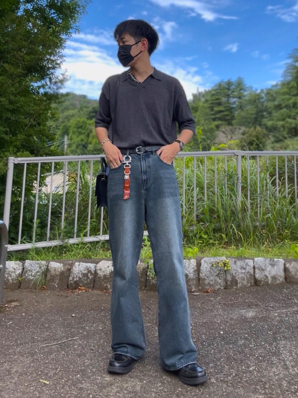 グレー系のポロシャツ、ブルー系のデニムパンツ、ブラック系のショルダーバッグを着用したメンズの夏コーディネートの3枚目の写真