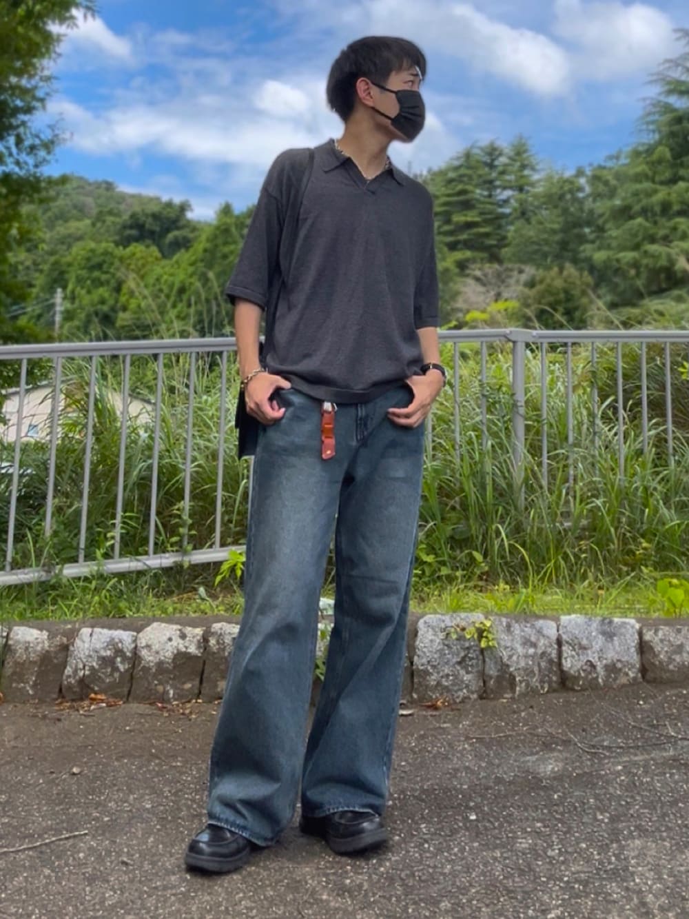 グレー系のポロシャツ、ブルー系のデニムパンツ、ブラック系のショルダーバッグを着用したメンズの夏コーディネートの2枚目の写真