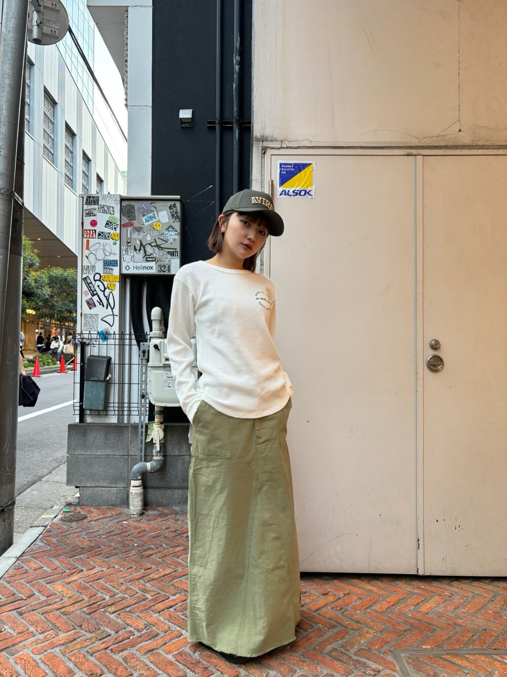 グリーン系のスカート、ホワイト系のトップス、グリーン系のキャップを着用したレディースの春コーディネートの2枚目の写真