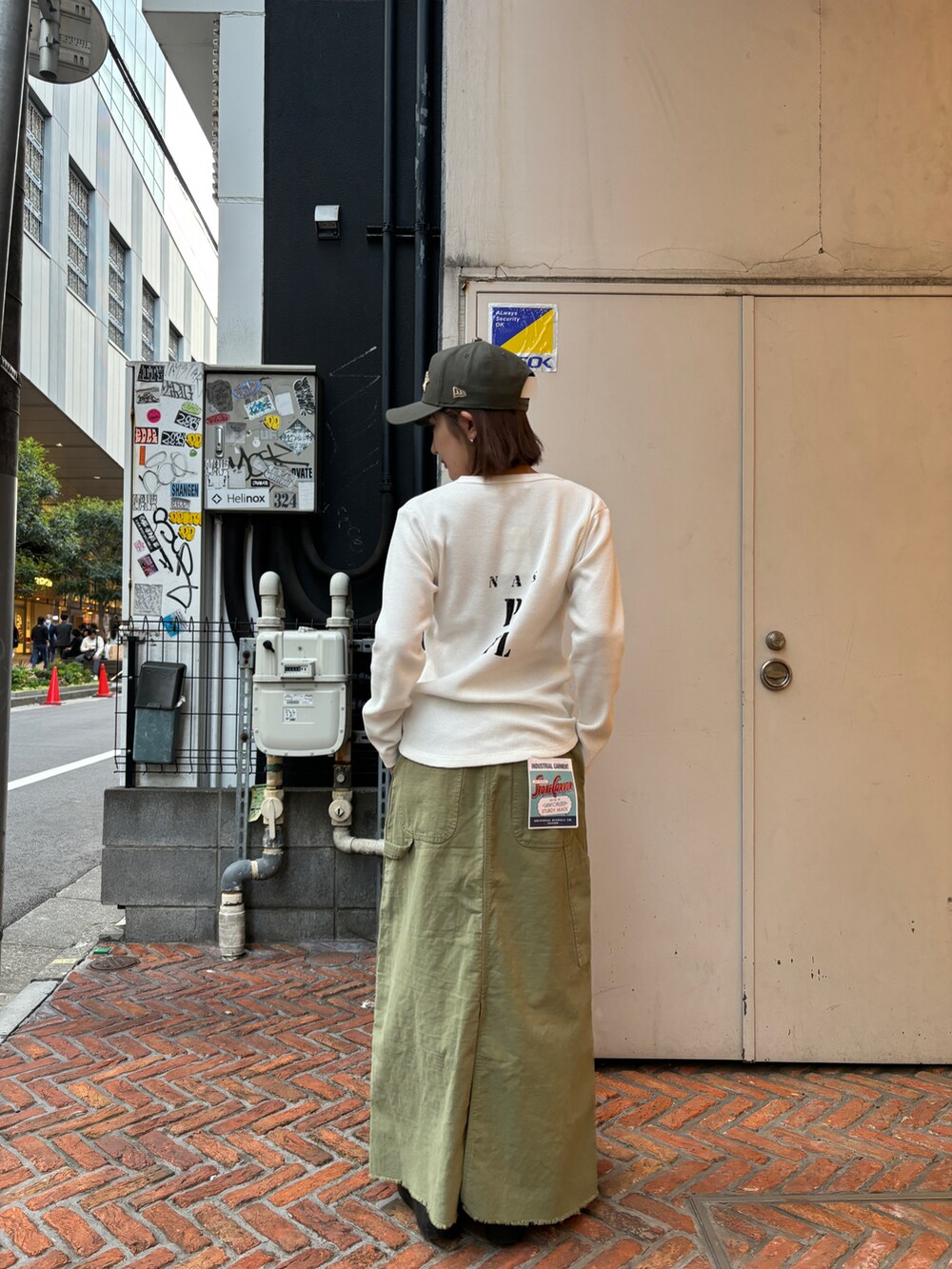 グリーン系のスカート、ホワイト系のトップス、グリーン系のキャップを着用したレディースの春コーディネートの3枚目の写真