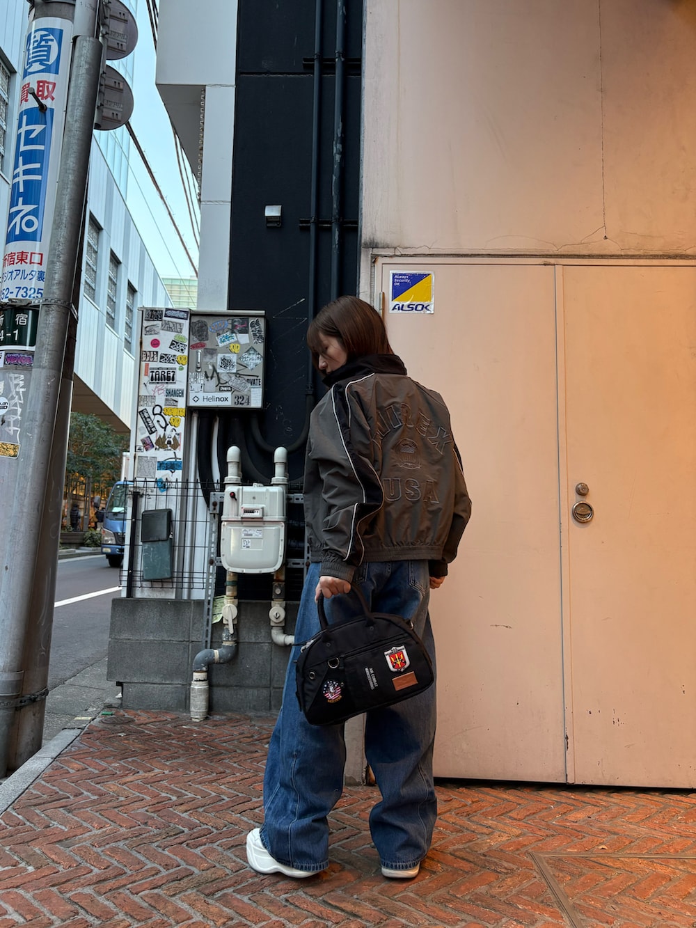 グレー系のナイロンジャケット、ピンク系のTシャツ/カットソー、ブラック系のボストンバッグを着用したレディースの冬コーディネートの2枚目の写真