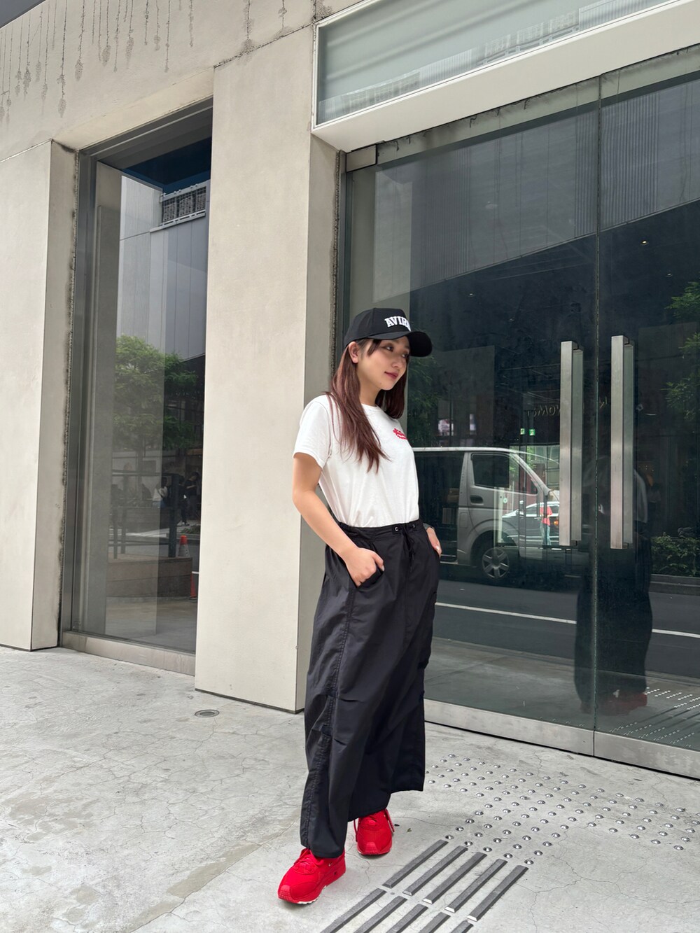 レッド系のTシャツ/カットソー、ブラック系のスカート、ブラック系のキャップを着用したレディースの夏コーディネートの4枚目の写真