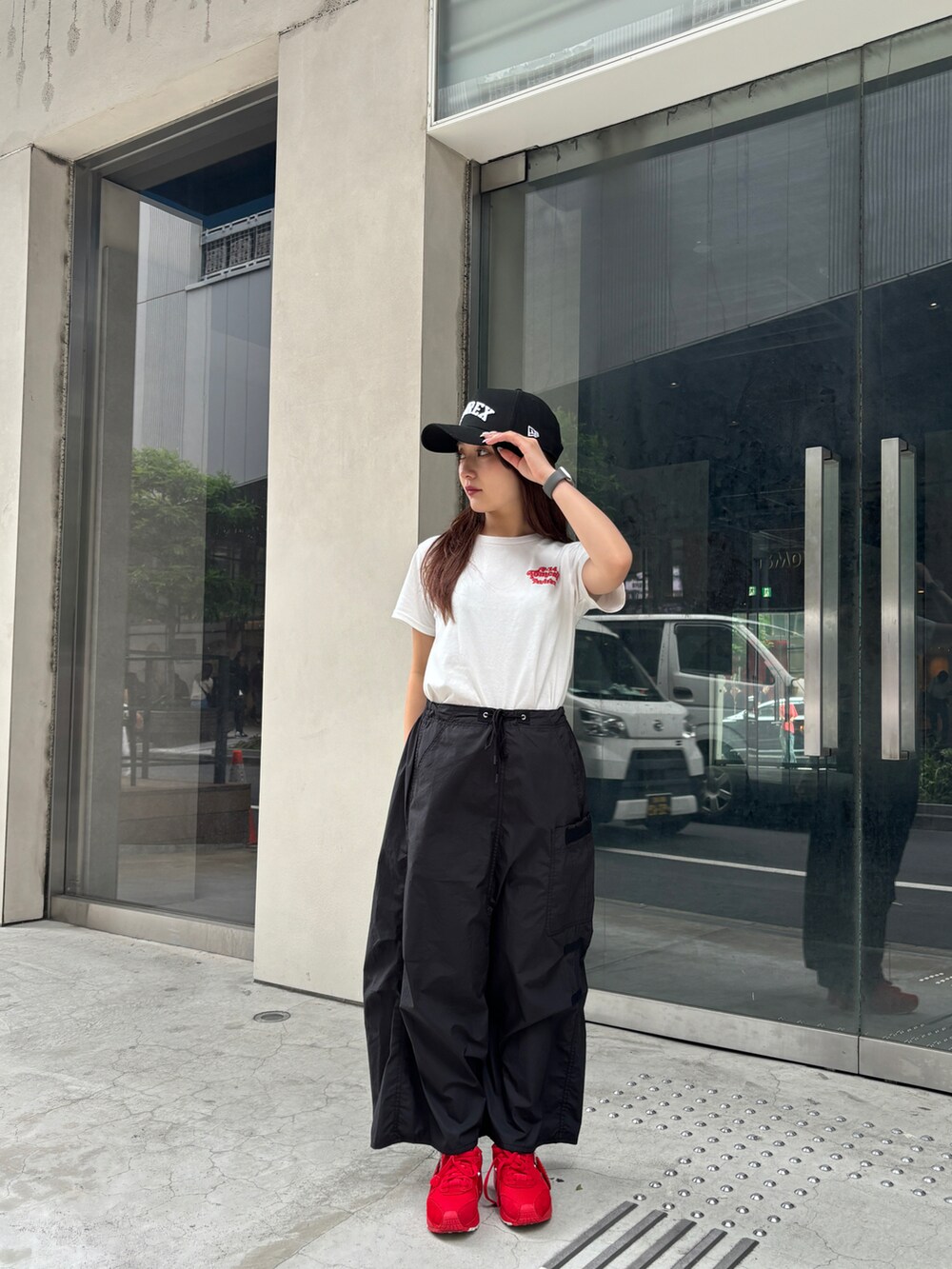 レッド系のTシャツ/カットソー、ブラック系のスカート、ブラック系のキャップを着用したレディースの夏コーディネートの3枚目の写真