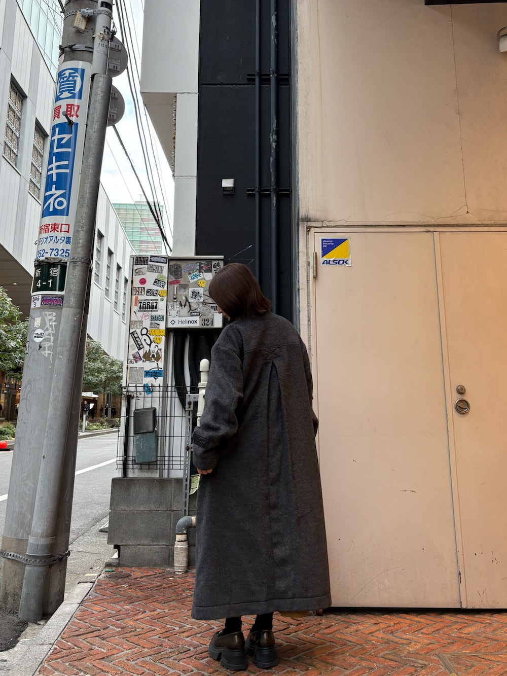 ブラック系のステンカラーコート、イエロー系のスカートを着用したレディースの冬コーディネートの4枚目の写真