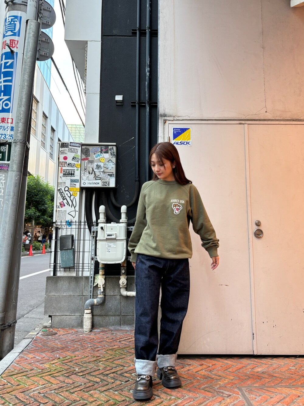 グリーン系のスウェット、ブルー系のデニムパンツを着用したレディースの秋コーディネートの2枚目の写真