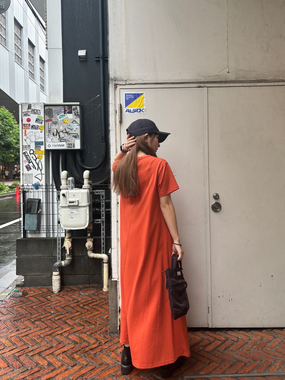 ブラック系のショルダーバッグ、オレンジ系のワンピース/ドレス、ブルー系のキャップを着用したレディースの春コーディネートの3枚目の写真