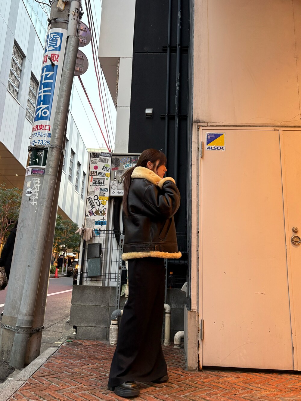 ブラウン系のムートンコートを着用したレディースの冬コーディネートの3枚目の写真