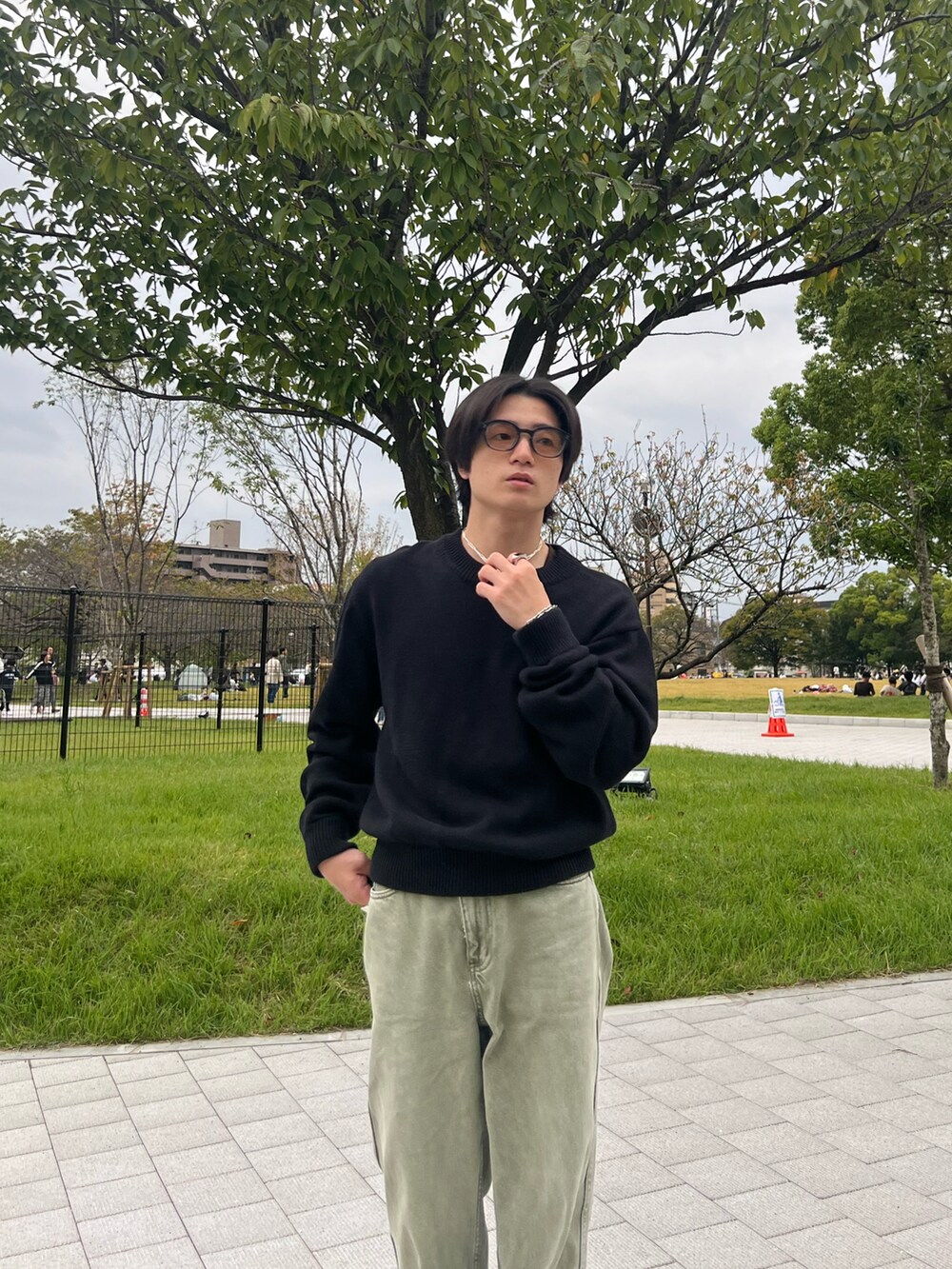 ブラック系のニット/セーター、ブラック系のチノパンツ、グレー系のスニーカーを着用したメンズの春コーディネートの4枚目の写真