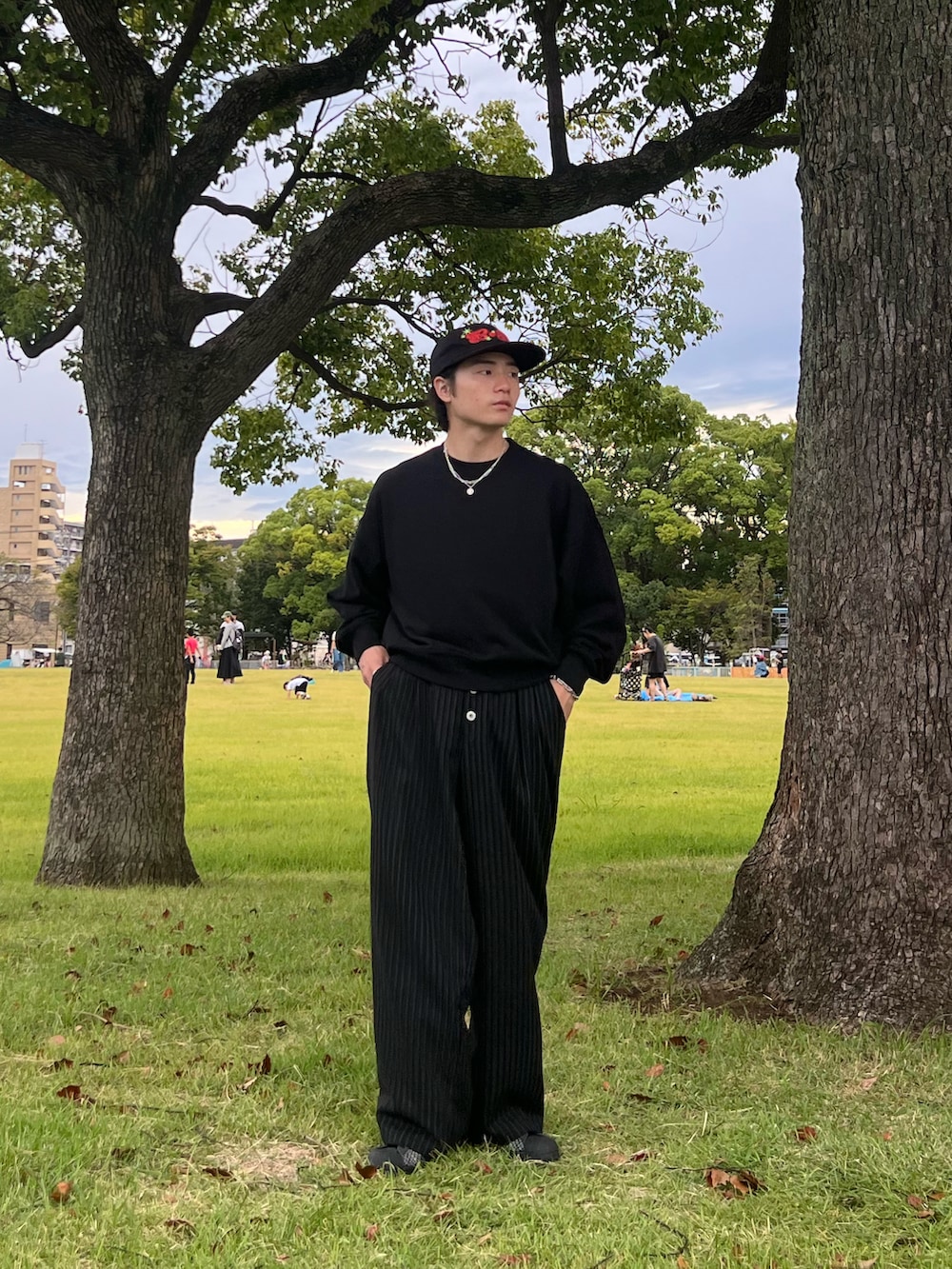 ブラック系のスウェット、ブラック系のスラックス、ブラック系のスニーカーを着用したメンズの春コーディネートの3枚目の写真