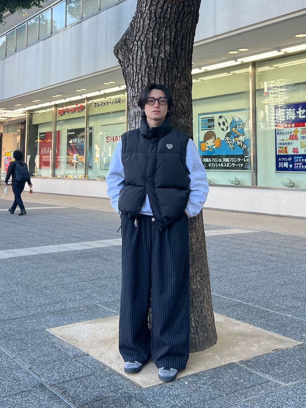 ブラック系のダウンベスト、グレー系のスウェット、ブラック系のスラックスを着用したメンズの春コーディネートの4枚目の写真