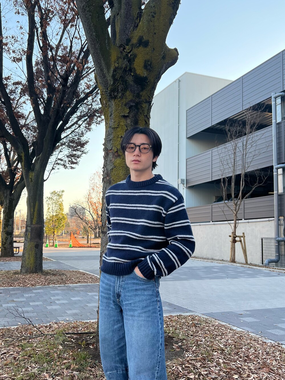 ブルー系のニット/セーター、ブルー系のデニムパンツ、ブラック系のスニーカーを着用したメンズの春コーディネートの4枚目の写真