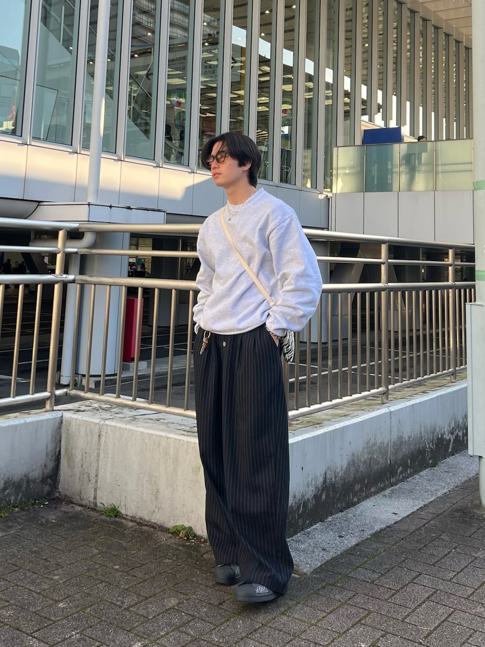 グレー系のスウェット、ブラック系のスラックス、ブラック系のスニーカーを着用したメンズの春コーディネートの4枚目の写真