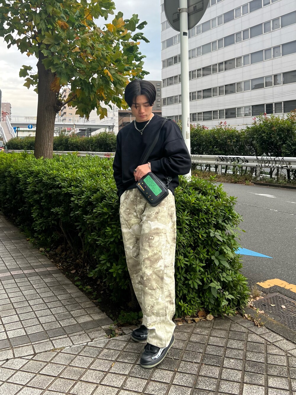 ブラック系のスウェット、グリーン系のチノパンツ、ブラック系のスニーカーを着用したメンズの春コーディネートの2枚目の写真