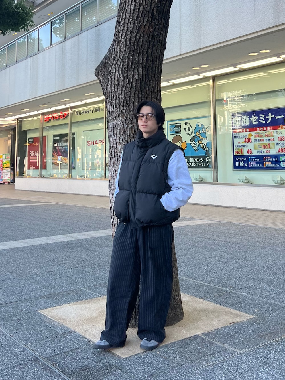 ブラック系のダウンベスト、グレー系のスウェット、ブラック系のスラックスを着用したメンズの春コーディネートの2枚目の写真