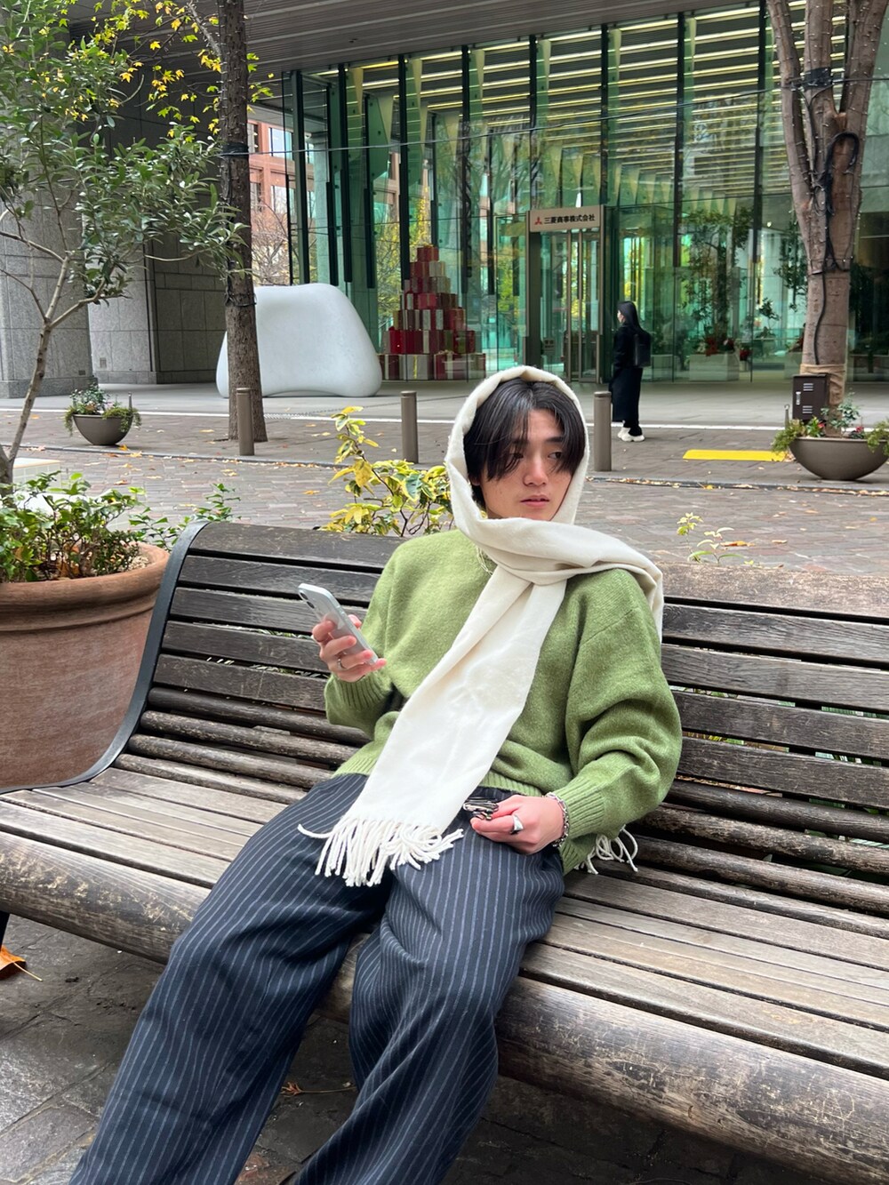 ブラック系のスラックス、グリーン系のニット/セーター、ブラック系のスニーカーを着用したメンズの春コーディネートの4枚目の写真