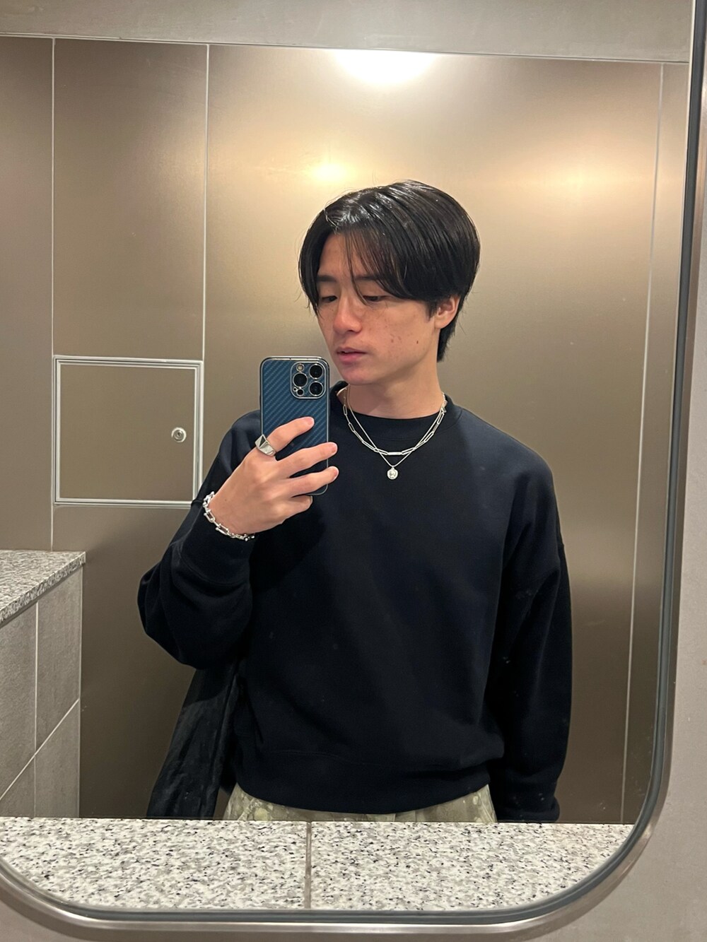 ブラック系のスウェット、グリーン系のチノパンツ、ブラック系のスニーカーを着用したメンズの春コーディネートの5枚目の写真