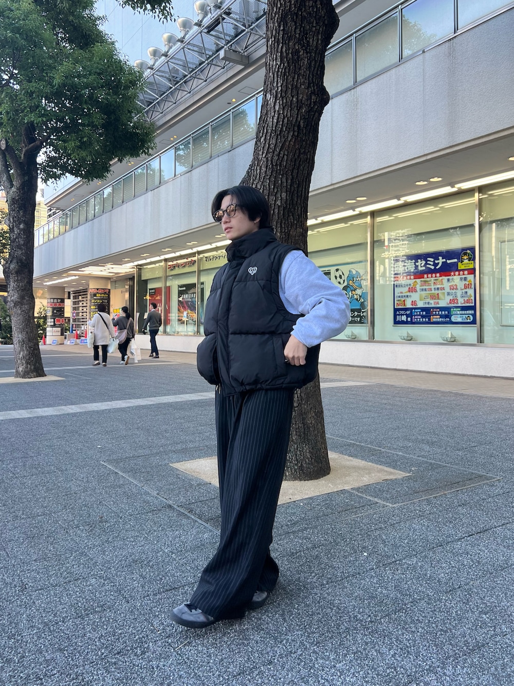 ブラック系のダウンベスト、グレー系のスウェット、ブラック系のスラックスを着用したメンズの春コーディネートの3枚目の写真